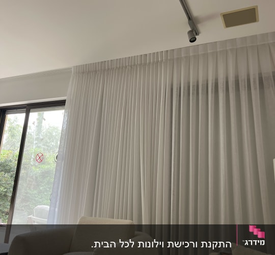 וילון לבן בסלון עם כורסאות ותאורה עליונה